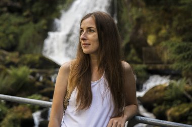 Şelalenin yanında duran sırt çantalı genç bir kadın..