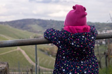 Şapkalı küçük çocuk doğanın manzarasına bakıyor..