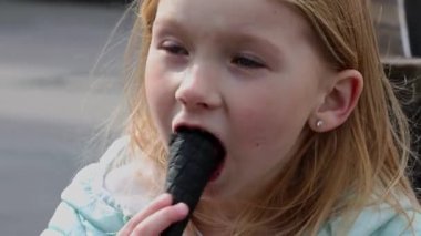 Girl eating ice cream cone on the street