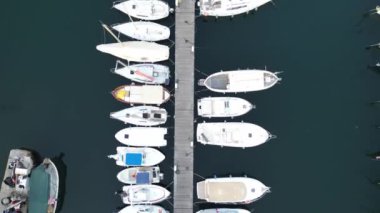 Tekneler ve yatlarla deniz koyunun drone görüntüsü.