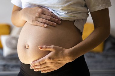 Hamile genç bir kadın bebeğinin karnını tutmasını dinliyor..