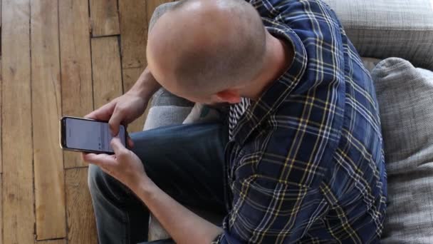Άνθρωπος Γράφει Ένα Μήνυμα Στο Τηλέφωνο Ενώ Κάθεται Στον Καναπέ — Αρχείο Βίντεο