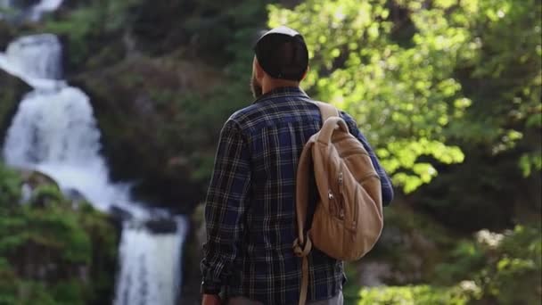 Człowiek Podziwia Górski Krajobraz Wodospad Podczas Wędrówki — Wideo stockowe