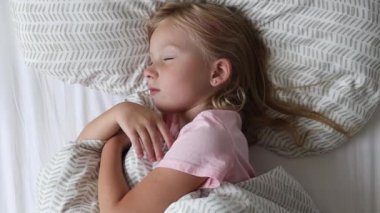 5 yaşındaki kız bir yatakta uyuyor.