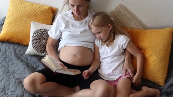 Schwangere Mutter Und Kleine Tochter Lesen Ein Buch — Stockvideo
