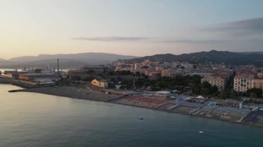 Gün batımında deniz kıyısındaki şehir, insansız hava aracı manzaralı.