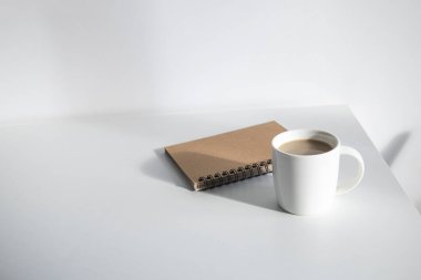 Beyaz bir masanın üzerinde kahve olan beyaz bir fincan. Üst manzara, düz uzanma.