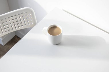 Beyaz bir masanın üzerinde kahve olan beyaz bir fincan. Üst manzara, düz uzanma.
