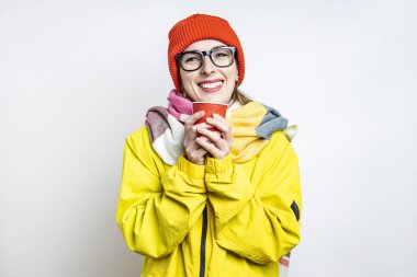 Hafif arka planda kağıt bardakla gülümseyen gözlüklü genç kadın.