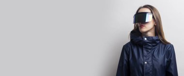 Sanal gerçeklik gözlüklü genç bir kadın arka planda yan tarafa bakıyor. Pankart.