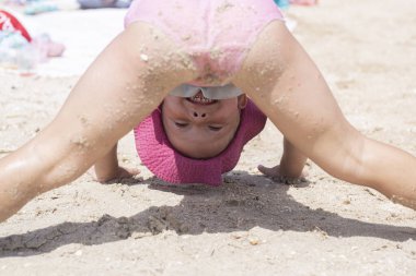 Sahilde mayo giymiş neşeli bir kız çocuğu oynanıyor.