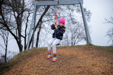 Çocuk parkta salıncakta sallanıyor..