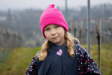 Bir çocuk üzüm bağları ve güzel bir manzara arasında duruyor..