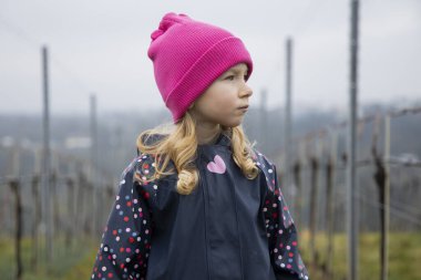 Bir çocuk üzüm bağları ve güzel bir manzara arasında duruyor..