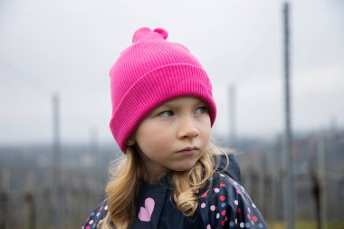 Çocuk yağmurlu bir günde üzüm bağları olan bir tepede duruyor..