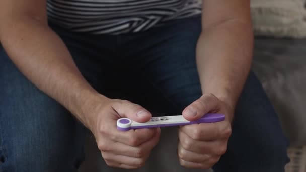 Mężczyzna Posiada Pozytywny Wynik Testu Ciążowego Dłoniach Podczas Siedzenia Kanapie — Wideo stockowe