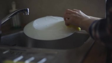 Kadın evde bulaşık yıkıyor.