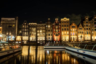 Damrak Amsterdam 'ın ana caddesi. Dansçı evleri olan Hollanda. Geceleri teknelerle suda yansıyan.