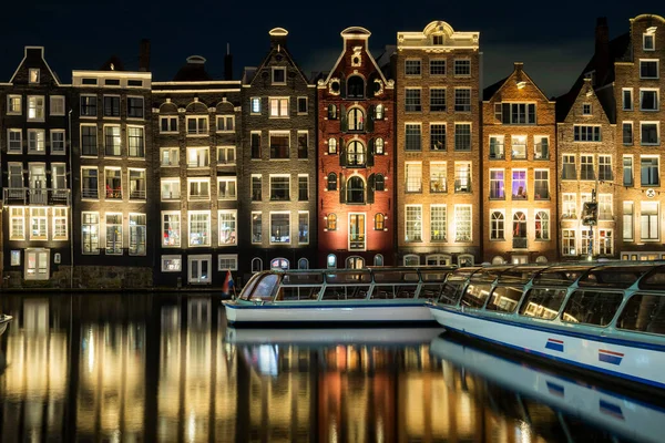 Damrak Amsterdam 'ın ana caddesi. Dansçı evleri olan Hollanda. Geceleri teknelerle suda yansıyan.