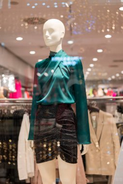 Mankenler bir mağazada sergileniyor ve alışveriş merkezinde giysileri var.