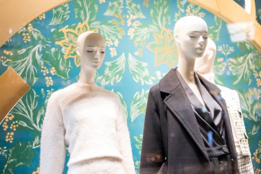 Mankenler bir mağazada sergileniyor ve alışveriş merkezinde giysileri var.