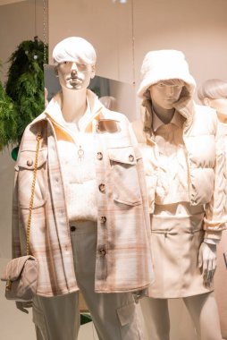 Mankenler bir mağazada sergileniyor ve alışveriş merkezinde giysileri var.