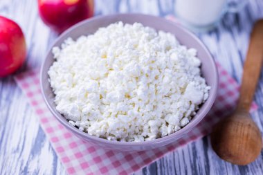 Süt ürünü süzme peynir bir tabak süt ve elma ile ahşap bir arka planda.