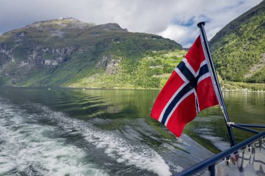 Norveç 'teki güzel körfez geiranger fiyordunun manzarası. Dağlar kayalar ve gemiden gelen bayrak.