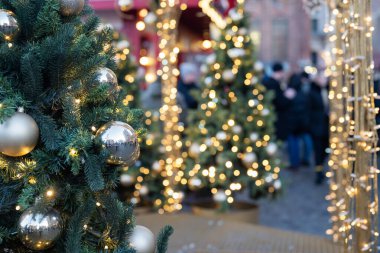 Noel ağacı, bir kenarı ve çelengi olan, bulanık bir arka planı olan bir festivalde.