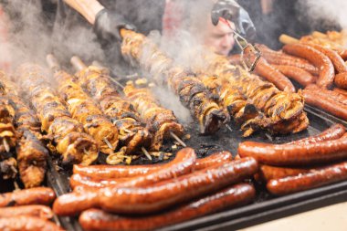 Satıcı, şehir merkezindeki Krakow Polonya 'daki Noel pazarında et ve sosis kızartıyor.