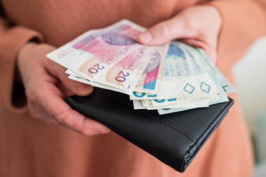 Elinde para tutan emekli kadın zloti emekli maaşı ve ödeme için bozuk para ödüyor.