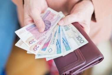 Elinde para tutan emekli kadın zloti emekli maaşı ve ödeme için bozuk para ödüyor.