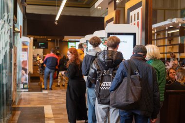 30 Mart 2025, Gdansk, Polonya. İnsanlar fast food restoranındaki self-servis kasasından sipariş veriyor.