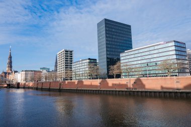 5 Eylül 2022, Hamburg, Almanya, Speicherstadt bölgesindeki nehirde tuğladan evler ve St. Katharinen Kilisesi manzaralı bir kanal.