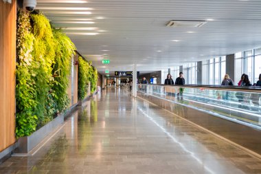 27 Nisan 2025 Stockholm İsveç, Arlanda Havalimanı terminalleri arasında yürüyen merdiven ve yolcular arasında geçiş.