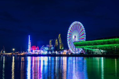 Polonya 'nın Szczecin şehrinin manzarası eğlence parkını cezbediyor. Tatil eğlenceleri geceleri suda yansıyor.