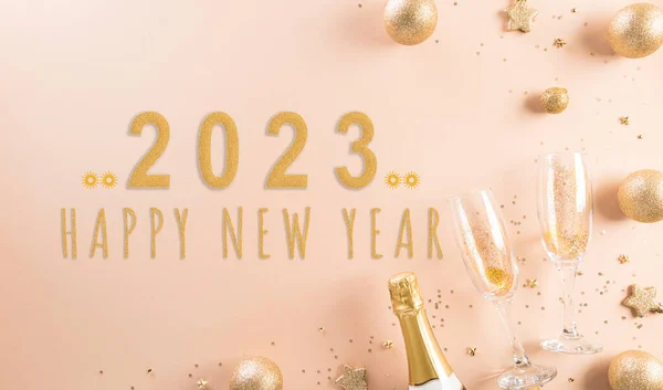 Happy New year celebration background concept. Golden christmas ball, star and champagne glasses on pastel background.