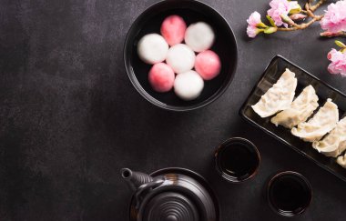 Tang Yuan (tatlı köfte topları), geleneksel bir sonbahar ortası mutfağı, Dongzhi (kış gündönümü) ve erik çiçeği ve pastel arka planda çay bulunan Çin yeni yılı..