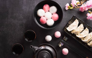 Tang Yuan (tatlı köfte topları), geleneksel bir sonbahar ortası mutfağı, Dongzhi (kış gündönümü) ve erik çiçeği ve koyu arkaplanda çay bulunan Çin yeni yılı..