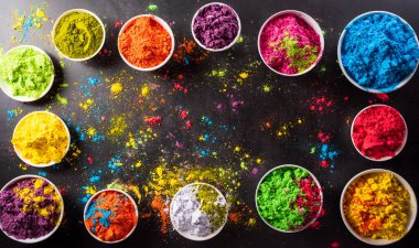 Koyu arkaplanda çok renkli holi boyası olan renkli holi tozunun üst görüntüsü. Mutlu Holi festivali dekorasyonu.