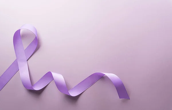 Purple ribbon on pastel paper background for supporting World Cancer Day campaign on February 4.