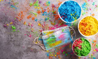 Renkli holi tozunun üst görüntüsü. Arka planda çok renkli tıbbi maske delikleri boyası var. Coronavirus 'taki Holi Festivali kutlu olsun.