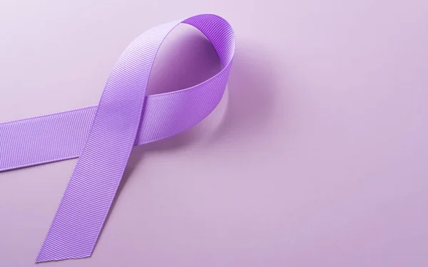 Purple ribbon on pastel paper background for supporting World Cancer Day campaign on February 4.
