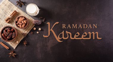 Top view of decoration Ramadan Kareem, dates fruit, milk, almond and the text on dark stone background.