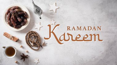 Ramadan food and drinks concept. Ramadan arabian lamp, wood rosary, tea, and dates fruit on stone background.
