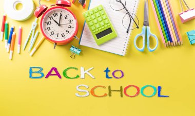 Eğitim ya da okula dönüş konsepti. Renkli okul malzemelerinin kitaplarla, renkli kalemlerle, hesap makinesiyle, ataçlarla ve pastel kağıt üzerinde elmayla en iyi görünümü.