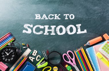 Eğitim ya da okula dönüş konsepti. Renkli okul malzemelerinin kitaplar, renk kalemleri, hesap makinesi, kalem kesme klipleri ve karatahta arka planıyla en iyi görünümü.