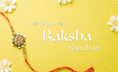 Raksha Bandhan, sarı arka planda güzel Rakhi ve Pirinç Taneleri olan Hint festivali. Geleneksel Hint bilekliği kız kardeşler ve erkek kardeşler arasındaki aşkın sembolüdür.