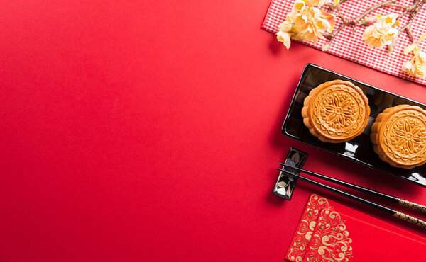 Chinese Mid-Autumn Festival concept made from mooncakes, tea and plum blossom. Chinese characters FU in the article refer to fortune good luck, wealth, money flow.