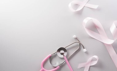 Pink ribbon and stethoscope on paper background for supporting breast cancer awareness month campaign.